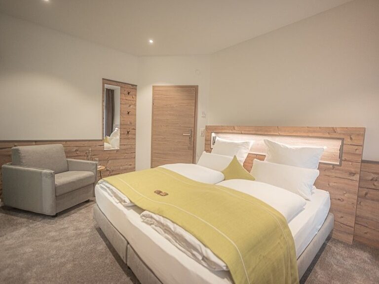 Ein gemütliches Schlafzimmer mit einem eleganten Bett und einem stilvollen Stuhl.