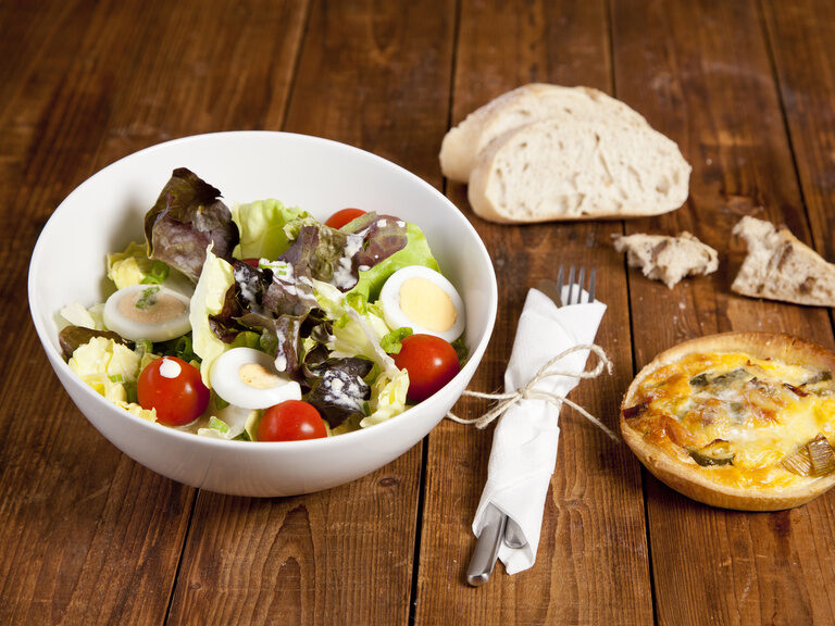 Frischer Salat und Brot auf einem rustikalen Holztisch.