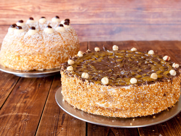 Zwei kunstvoll dekorierte Kuchen auf einem Holztisch.